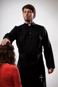 priest blessing woman on her knees