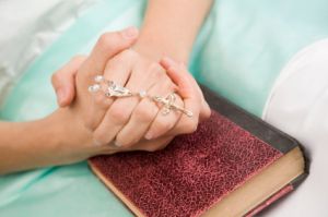 patient in hospital clutching rosary and bible