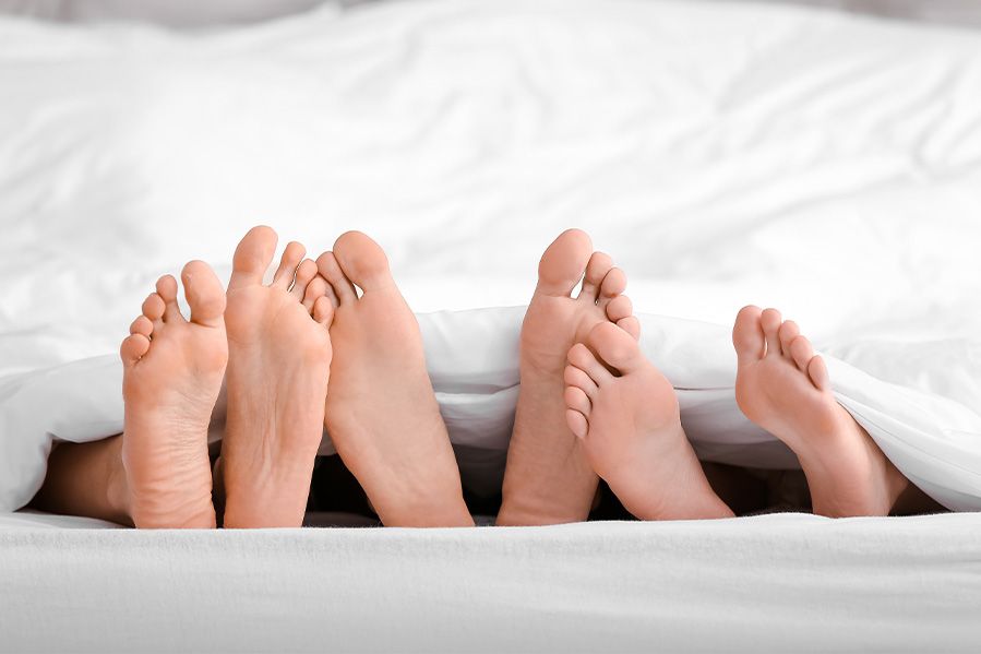 feet of people in bed, depiction of polygamy