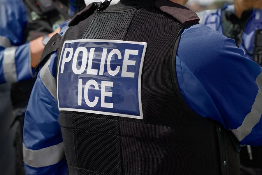 ice agent wearing tactical vest with 'POLICE ICE' written on back