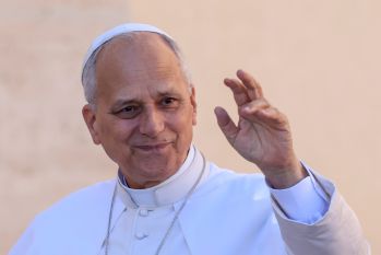 Pope Leo dressed in white raising his hand in greeting