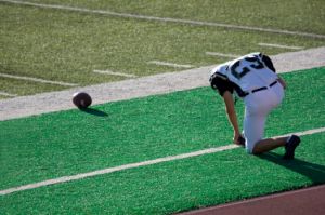 football player praying on sidelines