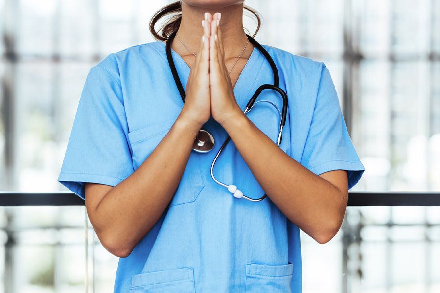 female doctor in scrubs praying