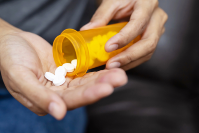 Person pouring prescription medication from a pill bottle into their hand.