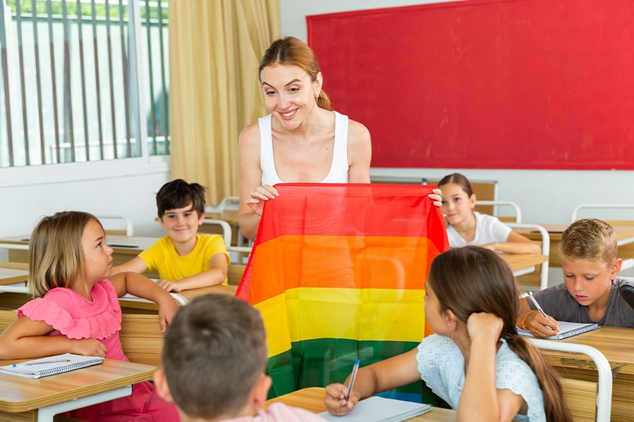 schoolteacher showing rainbow flag to children