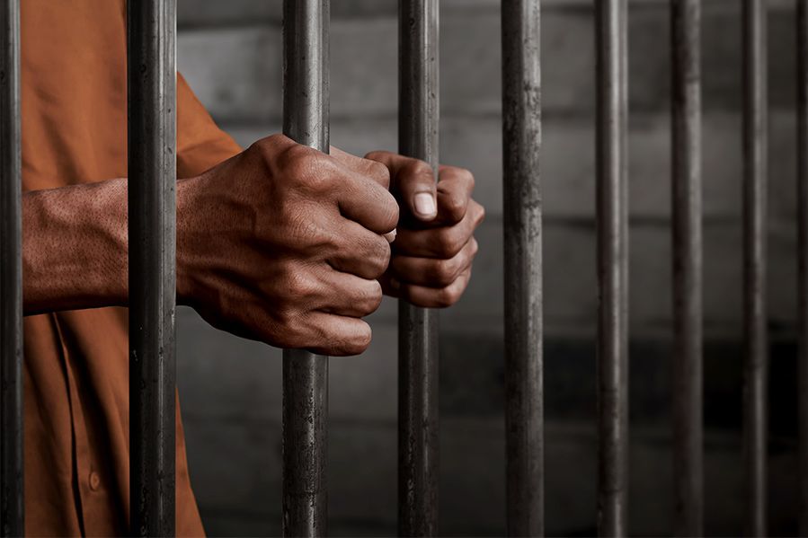 prisoner hands holding jail bars