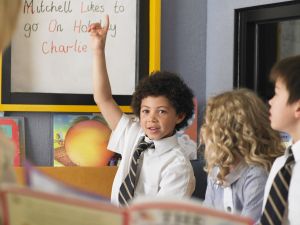 A child at a private religious school raising his hand in class. 