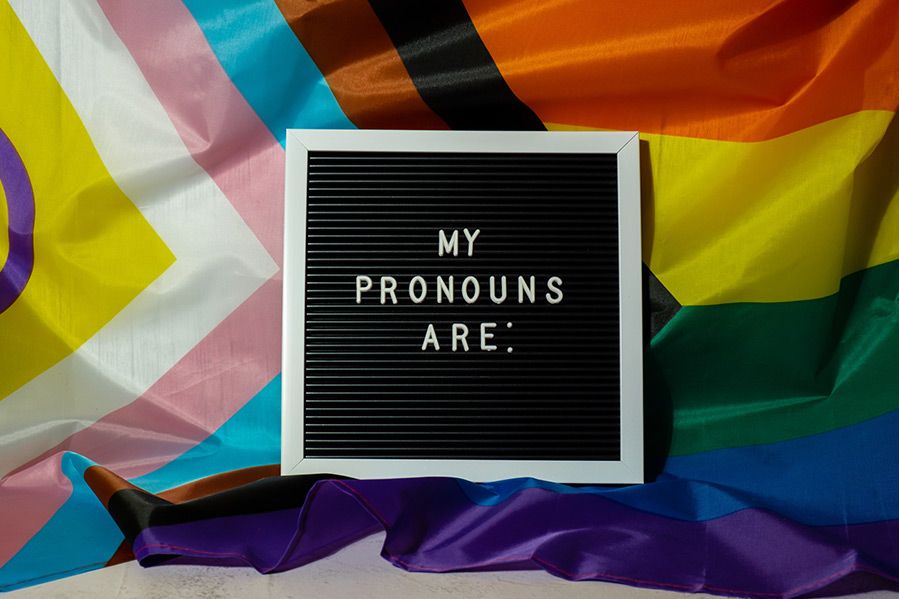 sign reading 'my pronouns are' on top of lgbtq flag