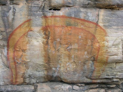 A cave painting featuring a colorful serpent arcing like a rainbow.