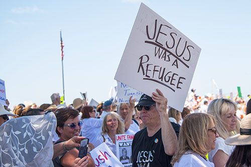A man at a protest holds a sign reading