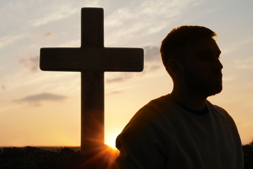 silhouetted man turning back on christian cross