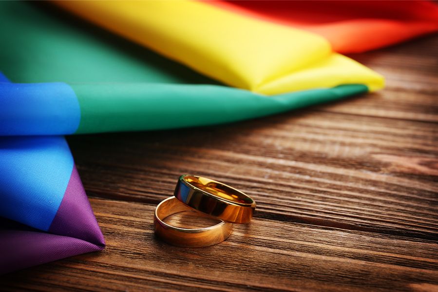 weddings bands and pride flag on table