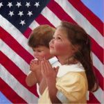 children praying in front of flag