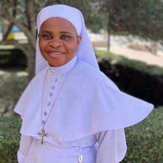 A photo of Sister Letty smiling outdoors wearing her white habit.