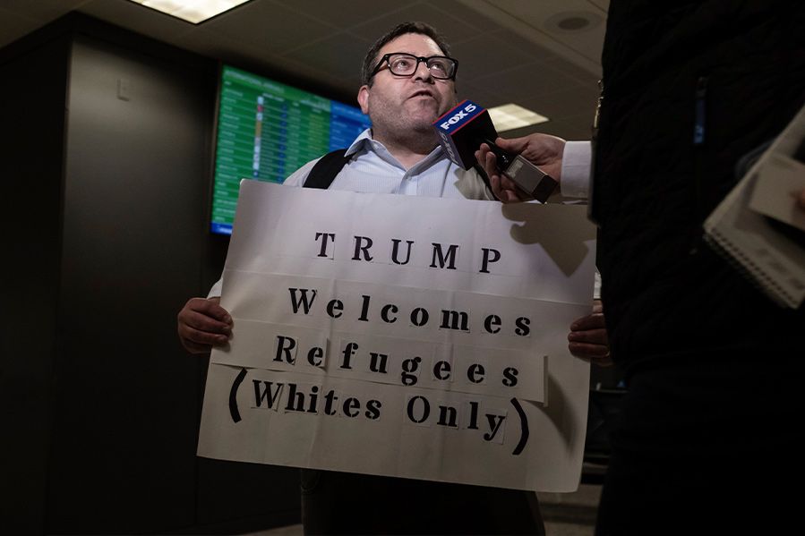 man wearing protest sign critical of donald trump