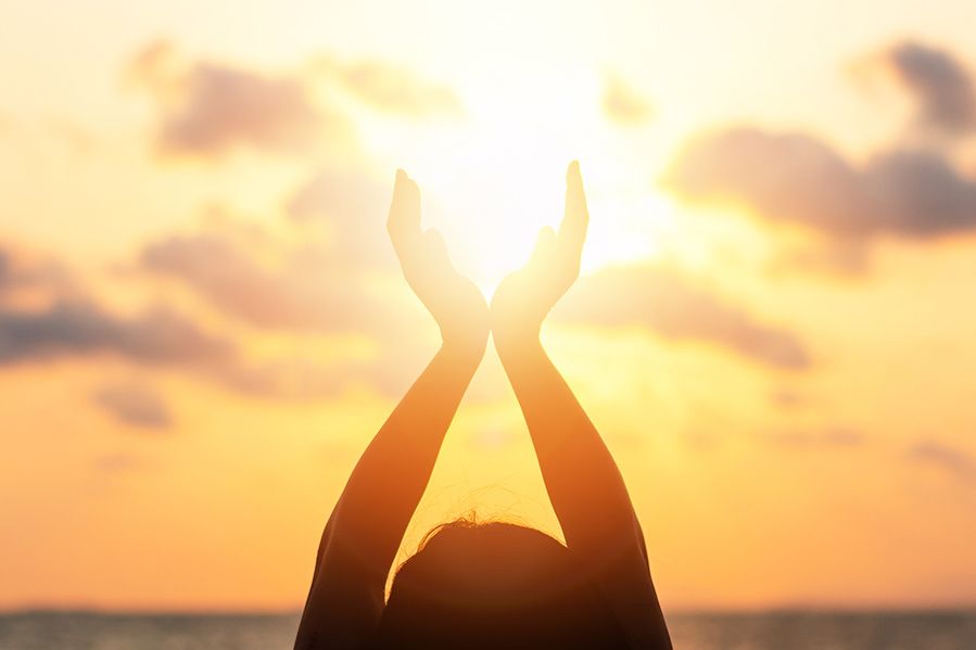 woman holding hands above head, praising sun