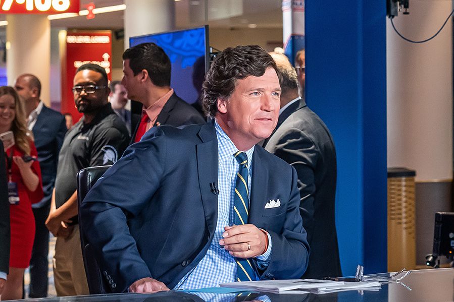 tucker carlson sitting at news desk