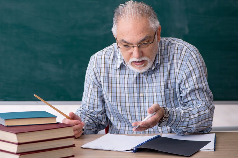angry teacher at desk looking at documents