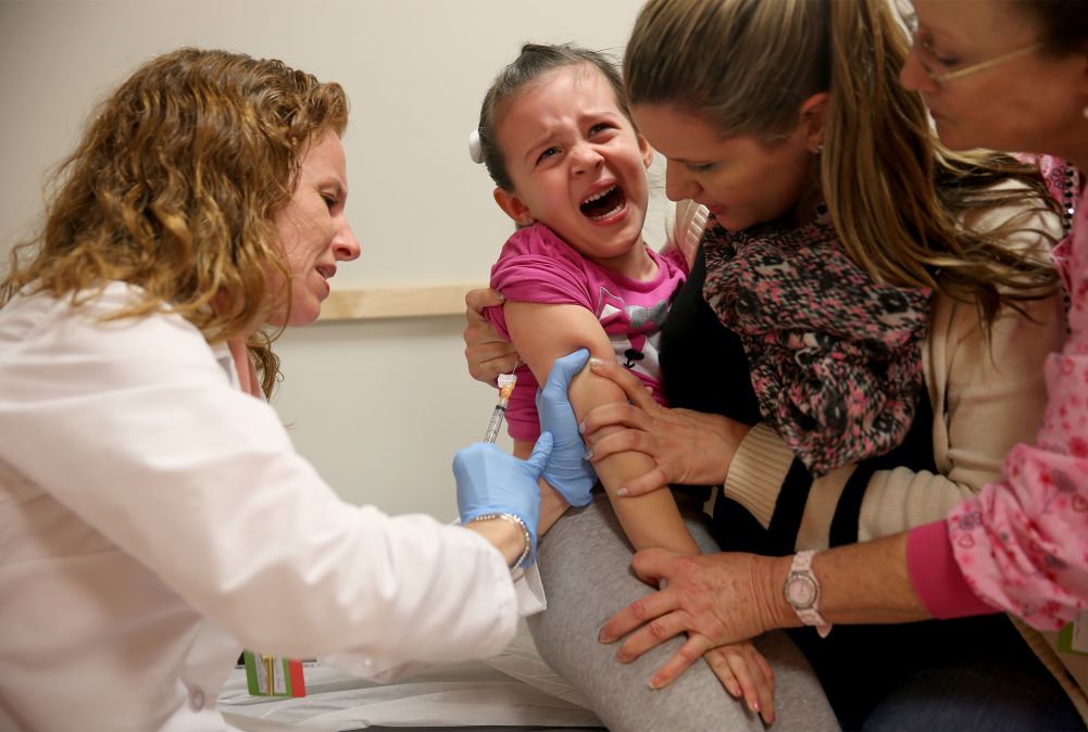 A crying child getting injected with a vaccine.