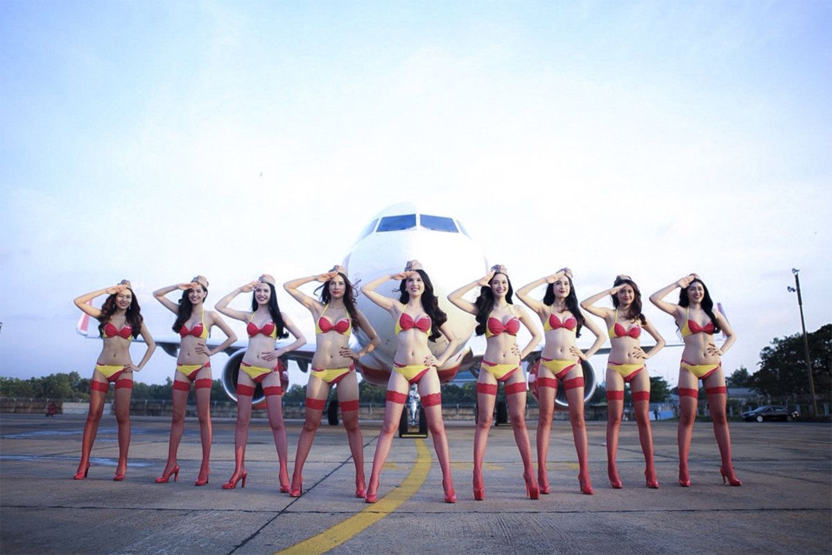 Bikini models pose in front of an airplaine