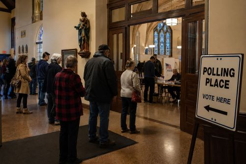 A group of people waiting to vote inside of a church that has been converted into a polling place.