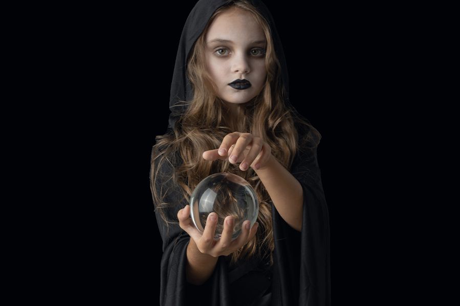 little girl dressed as witch holding crystal ball