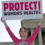 Woman protesting outside us capitol, holding 'protect women's health' sign