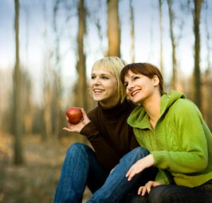 young lesbian couple eating apple outdoors