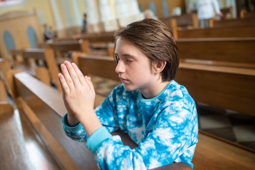 A young man praying in the pews