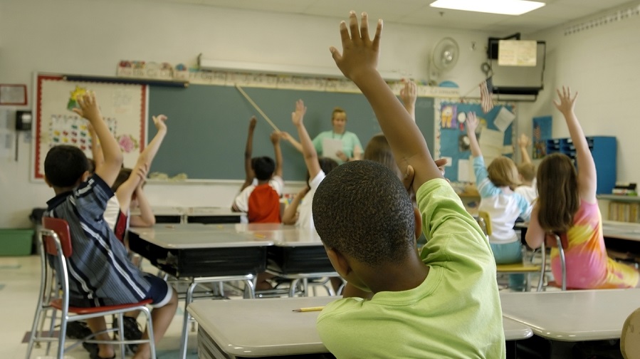 Children raising hands in classroom