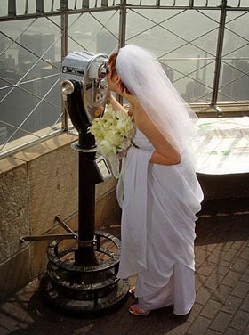 woman in wedding dress atop skyscraper looking out viewfinder