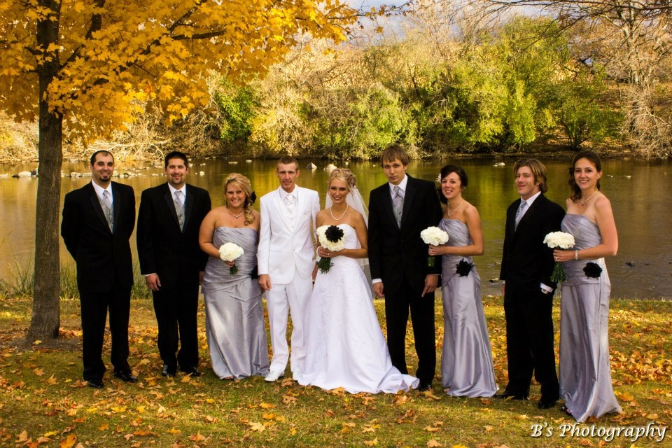 The wedding party poses for an outdoor photo near the river.