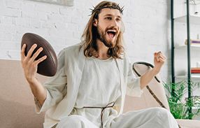 jesus christ holding football and cheering on couch while watching super bowl