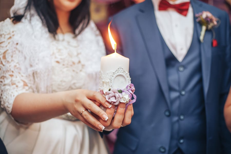Bride and groom holding unity candle at wedding