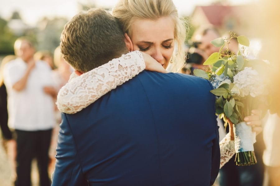 Tearful bride hugging new husband in personal moment at wedding