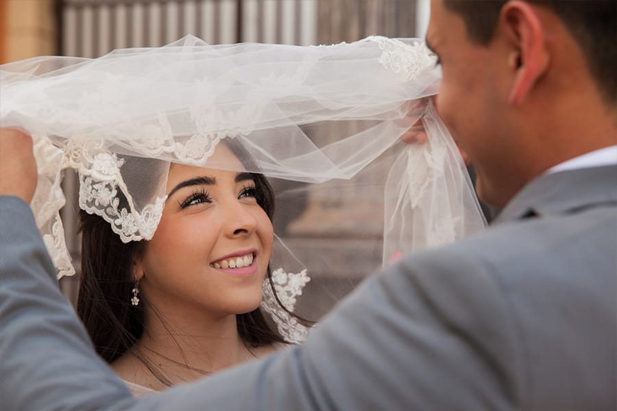 Husband lifting veil over Spanish bride's face