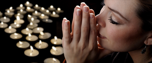Woman Praying Prayer Meditation woman close-up with tea lights floating in the background