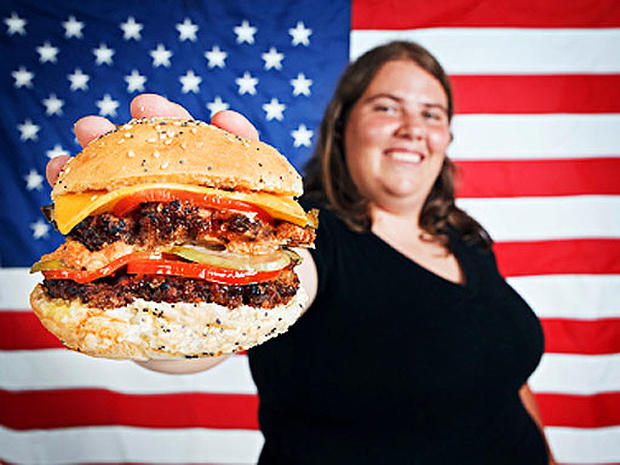 An overweight American holding a cheeseburger