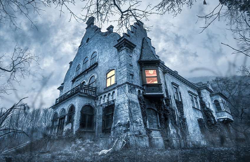 A haunted house viewed through the trees.
